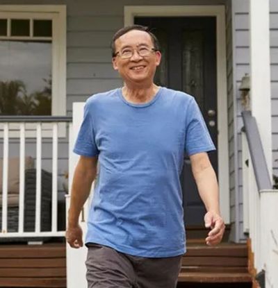 Smiling man in a blue t‑shirt and pants leaving his house to go for a walk
